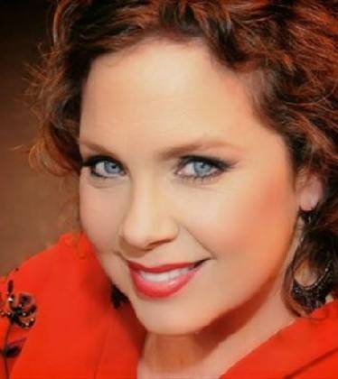 Close-up portrait of a smiling woman with curly hair and blue eyes.