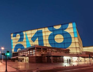 Modern building with large numbers displayed on its facade at night.